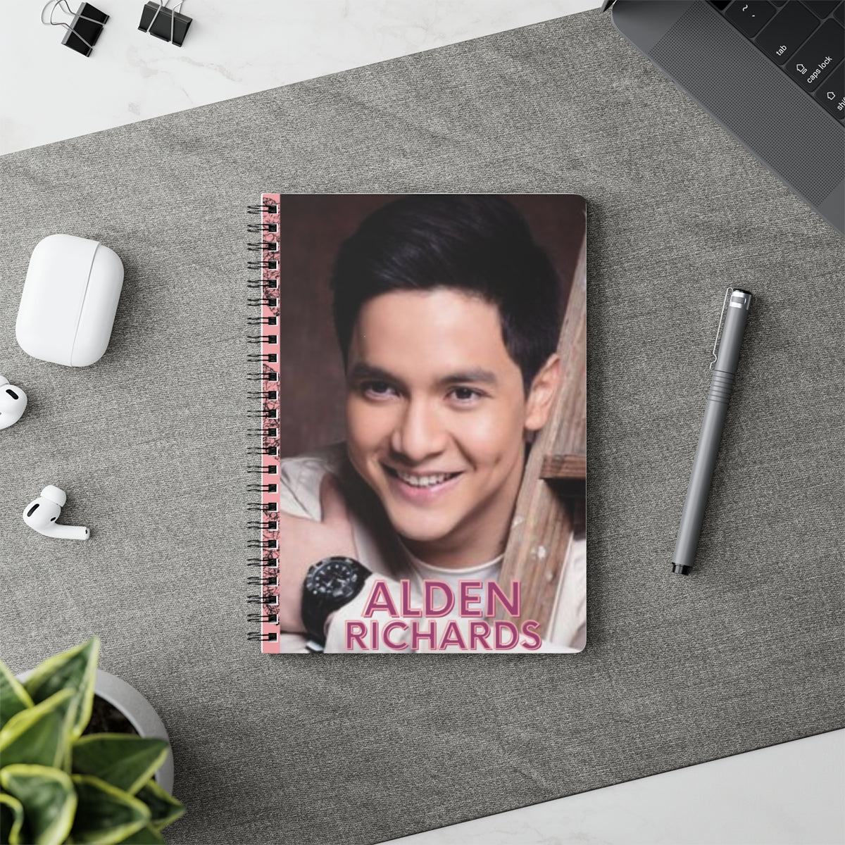 Alden Richards themed spiral notebook on a workspace with a pen and headphones, perfect for stylish note-taking.