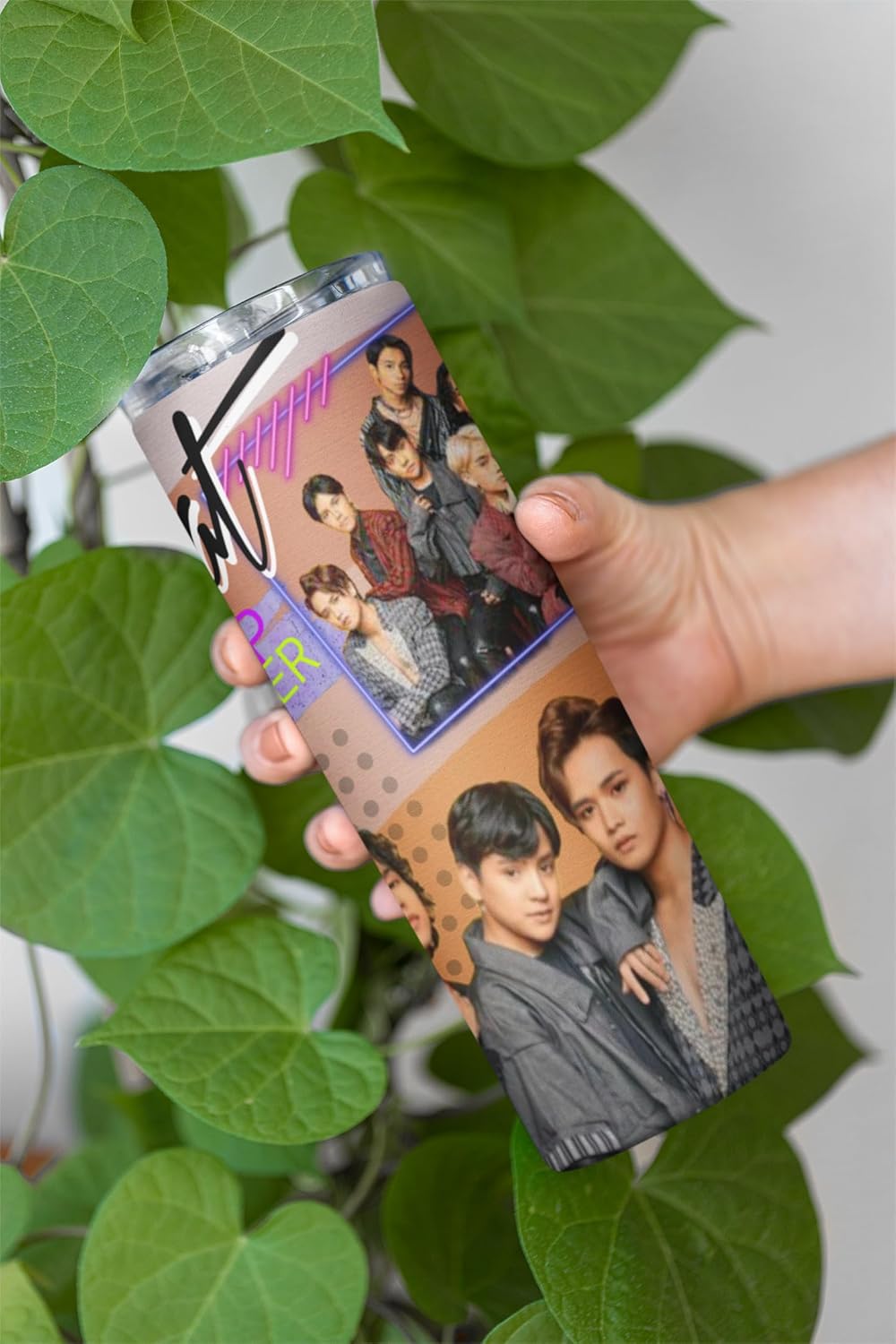 P-Pop Alamat 20 oz tumbler held among green leaves, featuring vibrant design and images of popular Filipino artists.